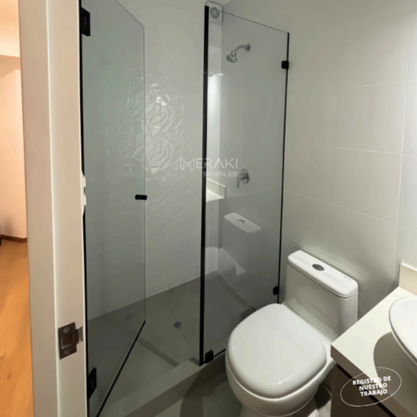 Mampara batiente de vidrio templado con grabado, instalada junto al inodoro de un baño