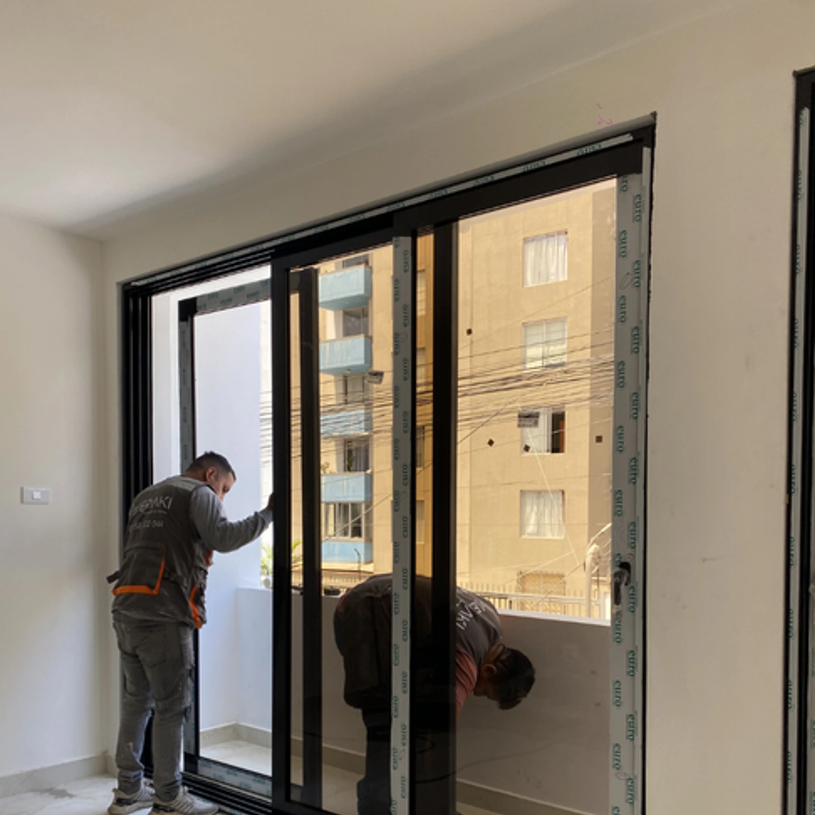 Dos instaladores de Meraki colocando el panel de vidrio de una mampara corrediza