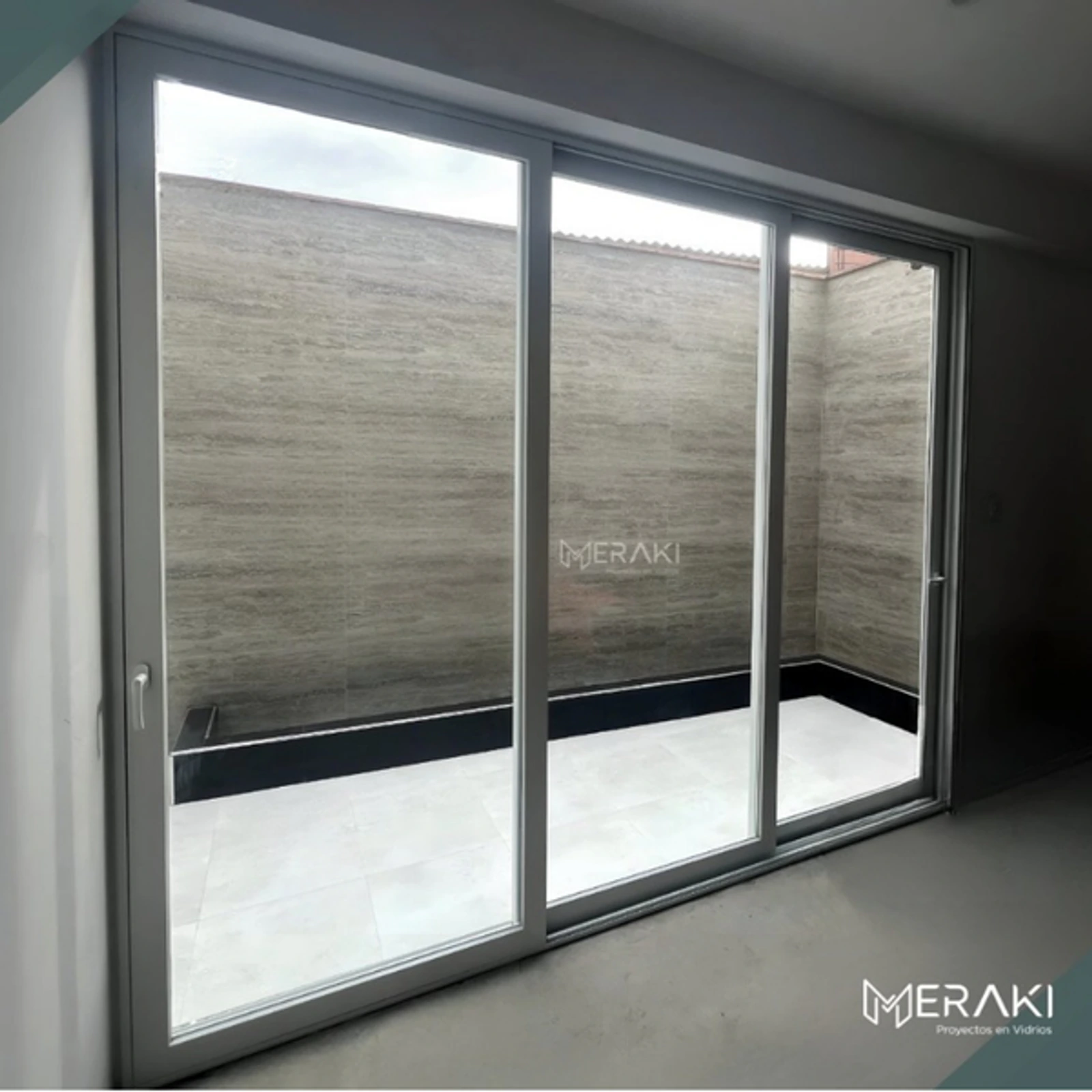 Mampara corrediza de perfilería gris con salida a un patio interior