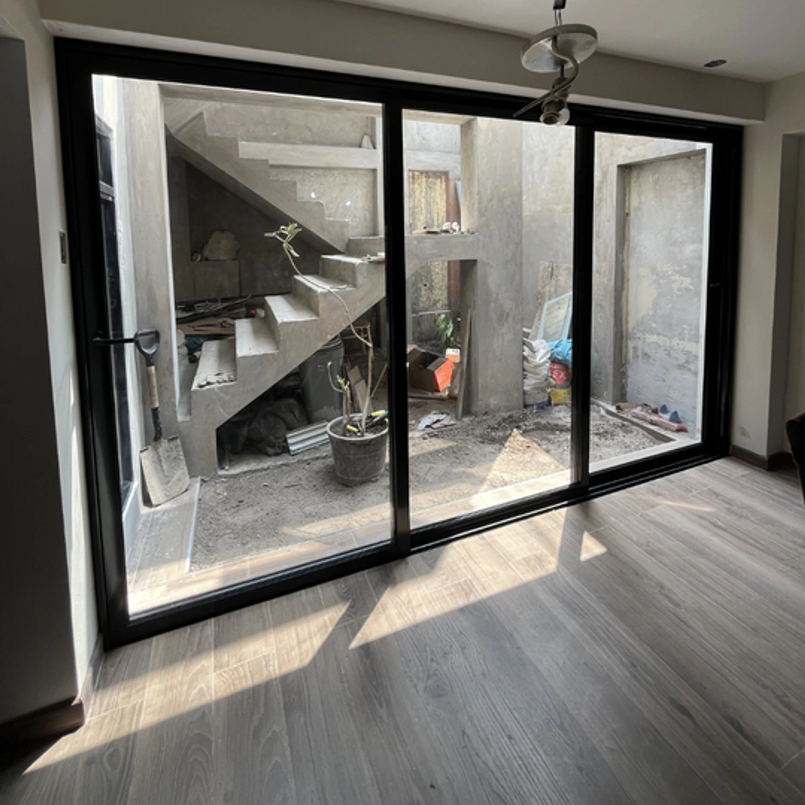 Mampara corrediza de perfilería negra bajo una escalera, en una vivienda en obra