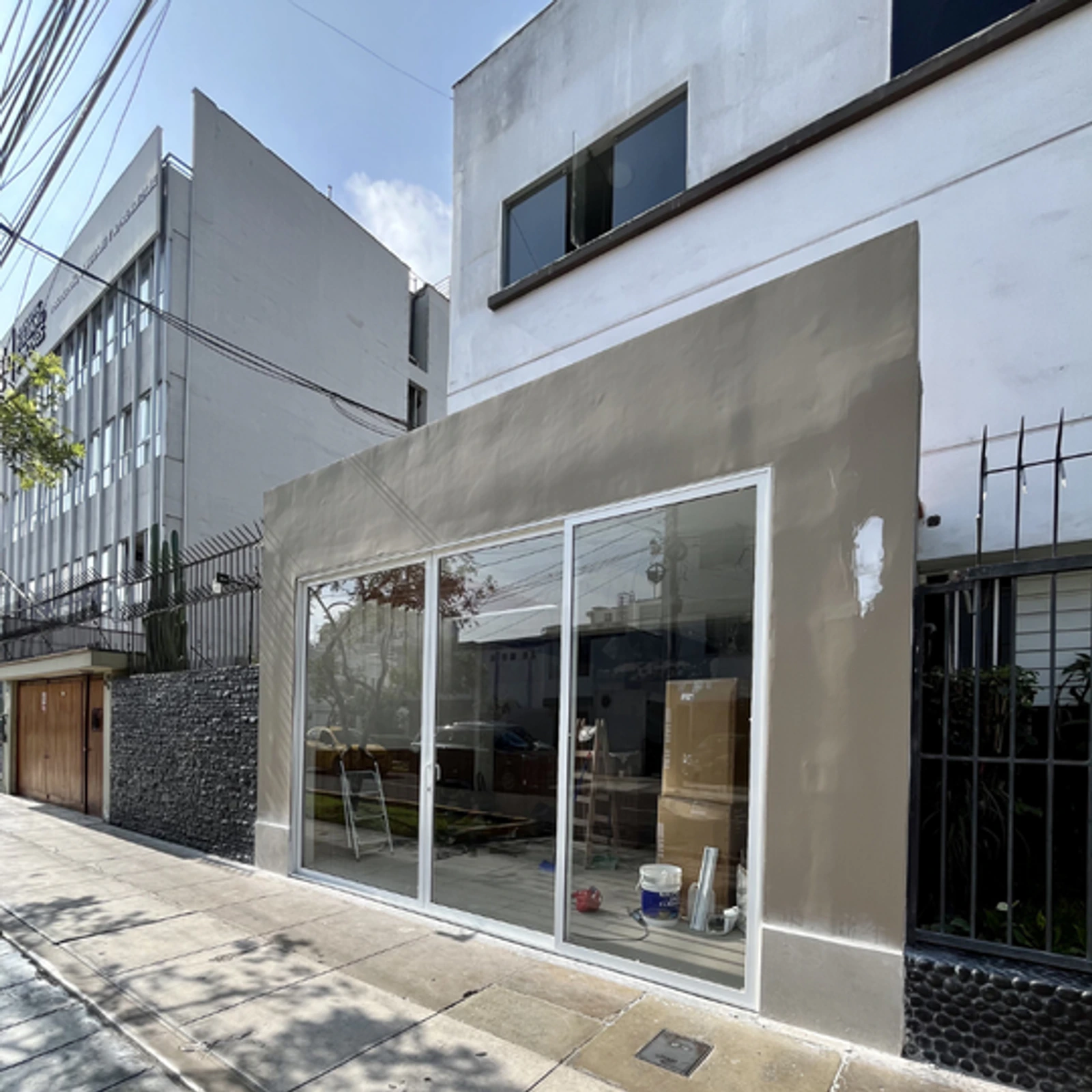 Mampara corrediza de perfilería blanca en la fachada de un local comercial
