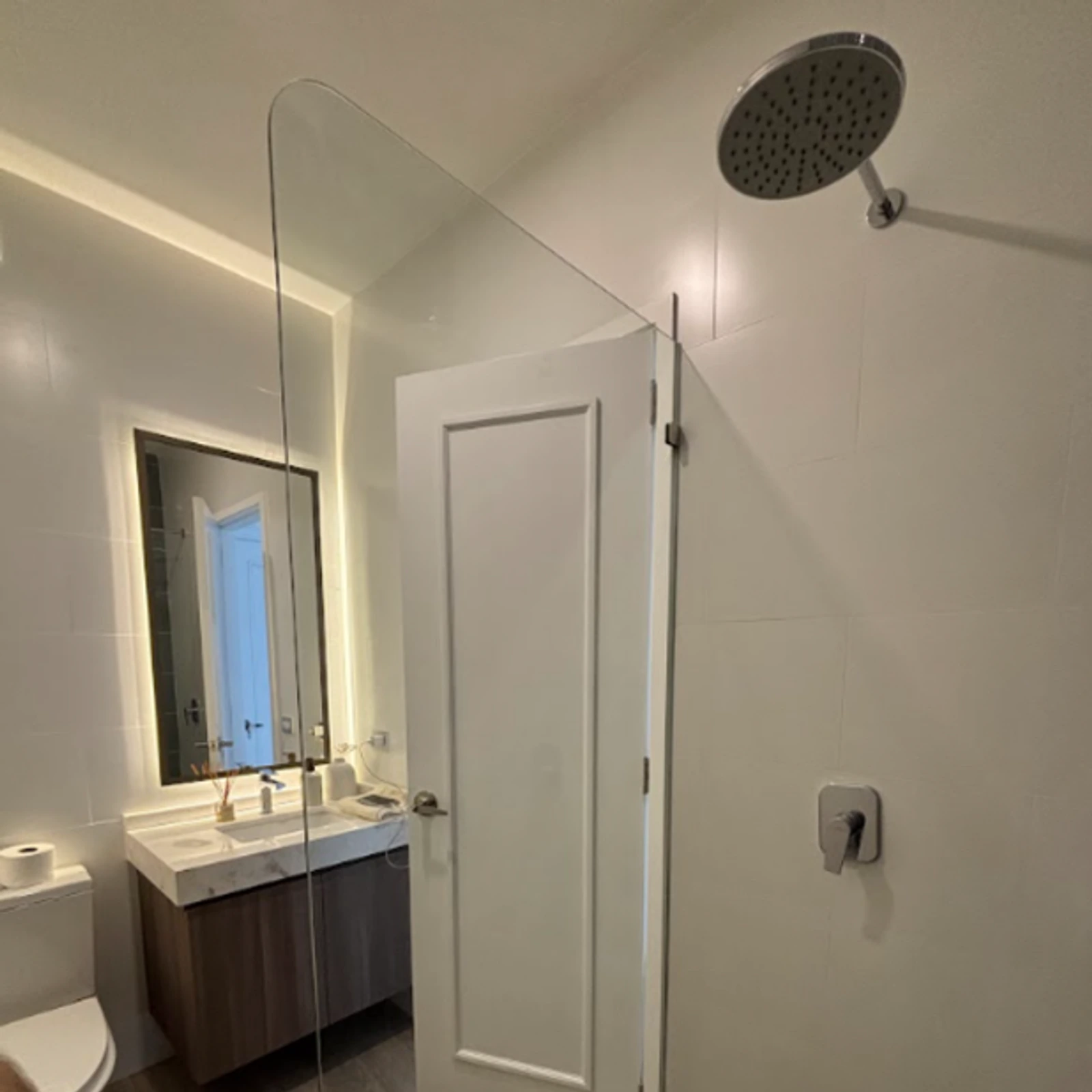 Panel fijo de vidrio templado separando la zona de ducha del lavamanos