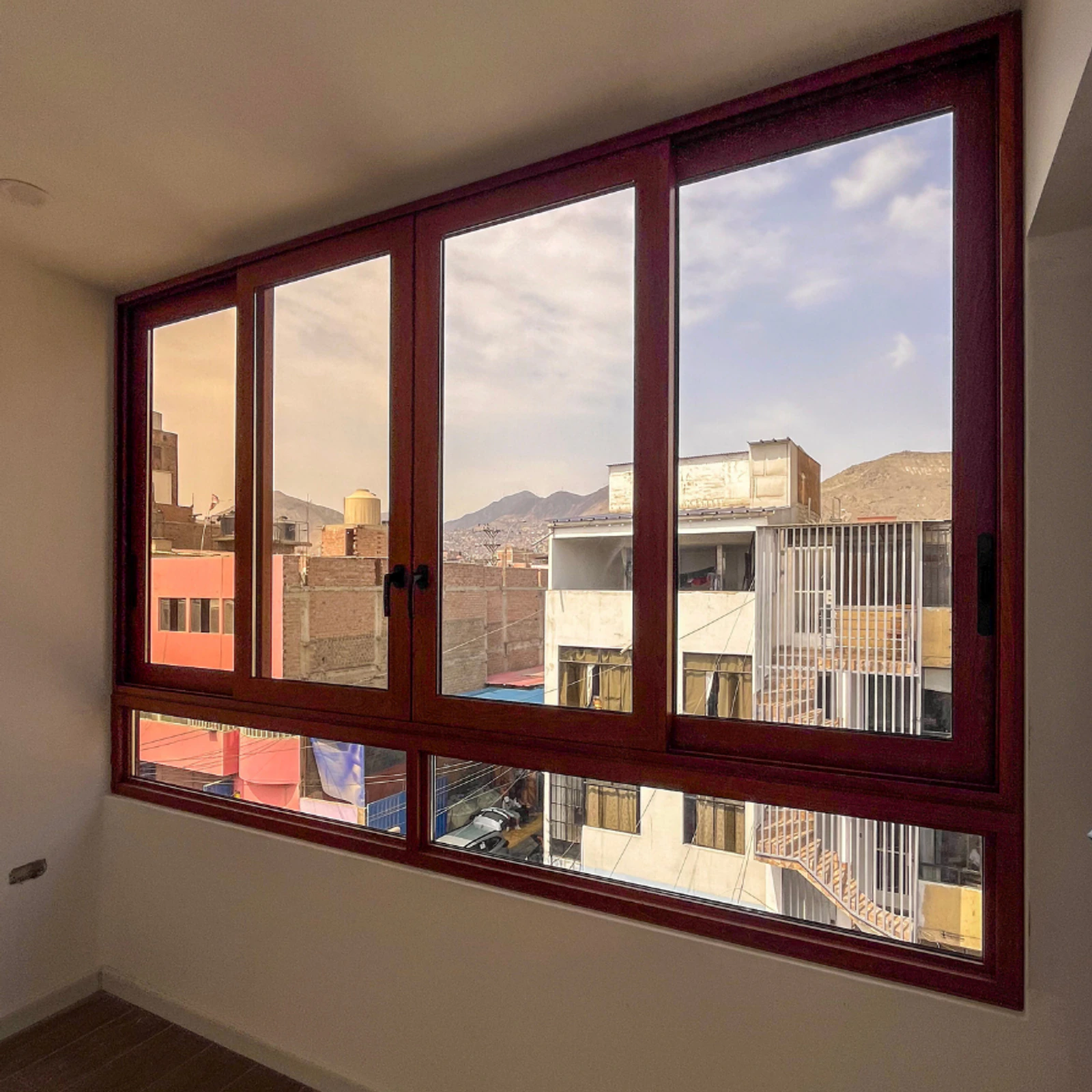 Ventana corrediza de cuatro hojas con perfilería color madera y vista a la calle
