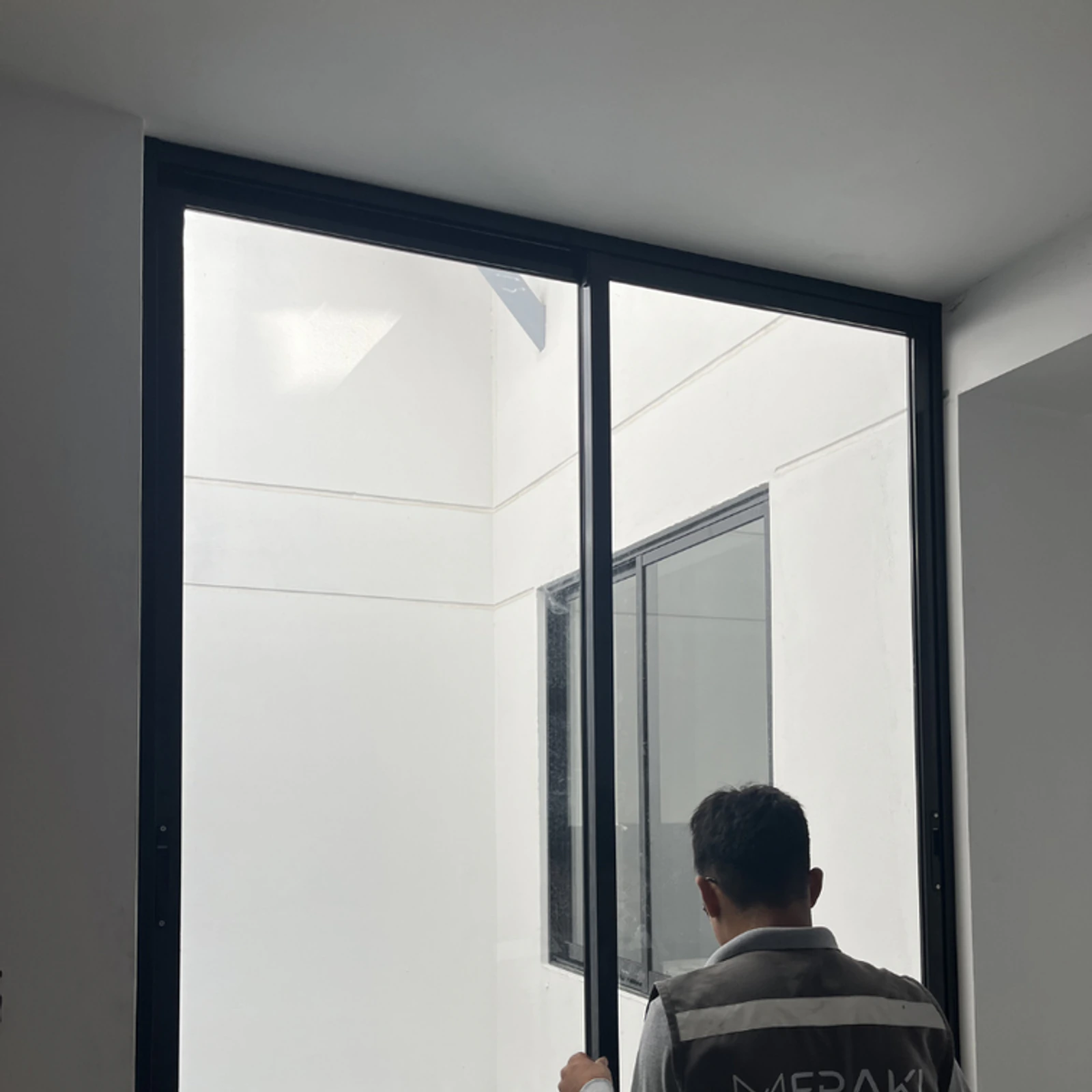 Técnico de Meraki ajustando una ventana corrediza de perfilería negra