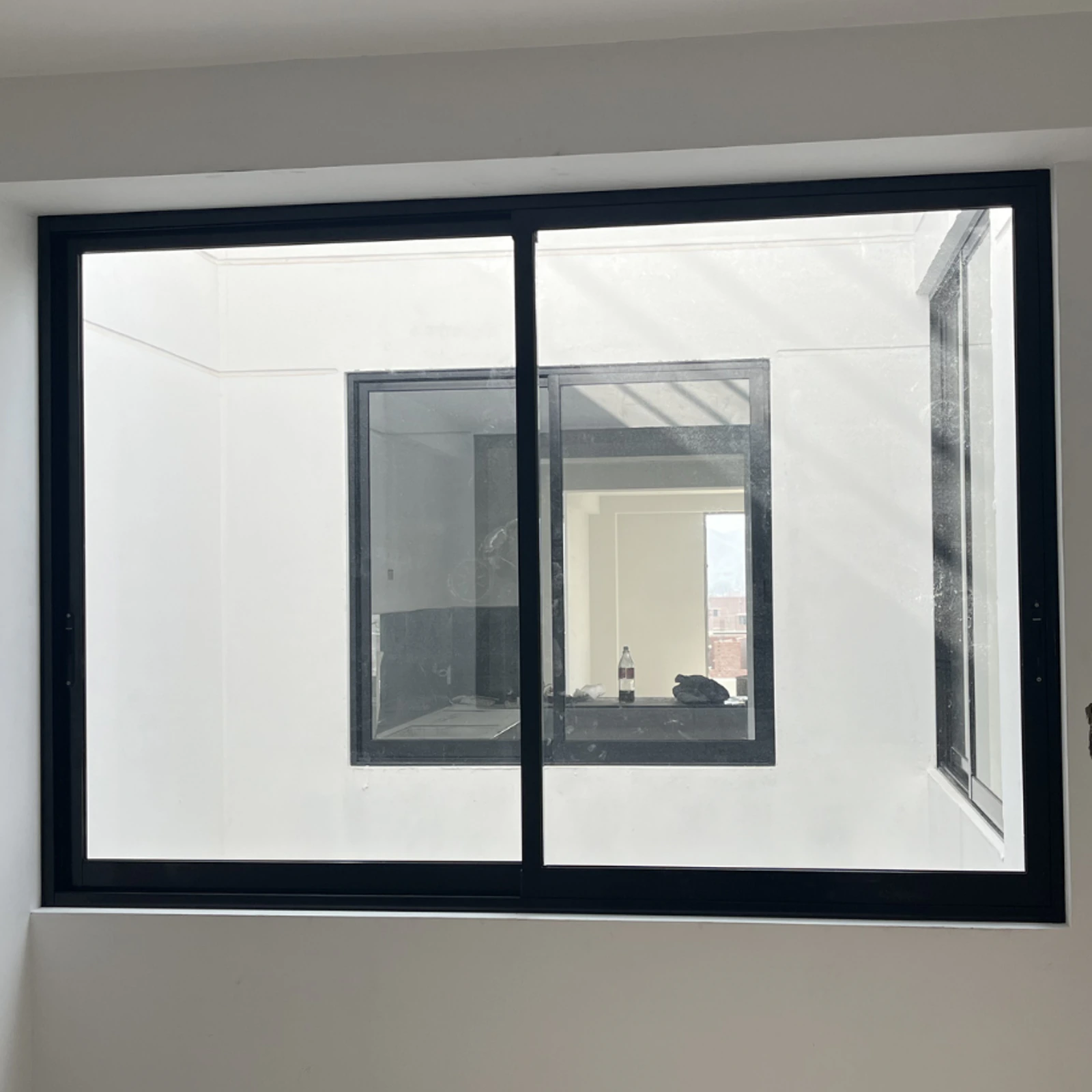 Ventana corrediza de perfilería negra que comunica dos ambientes interiores
