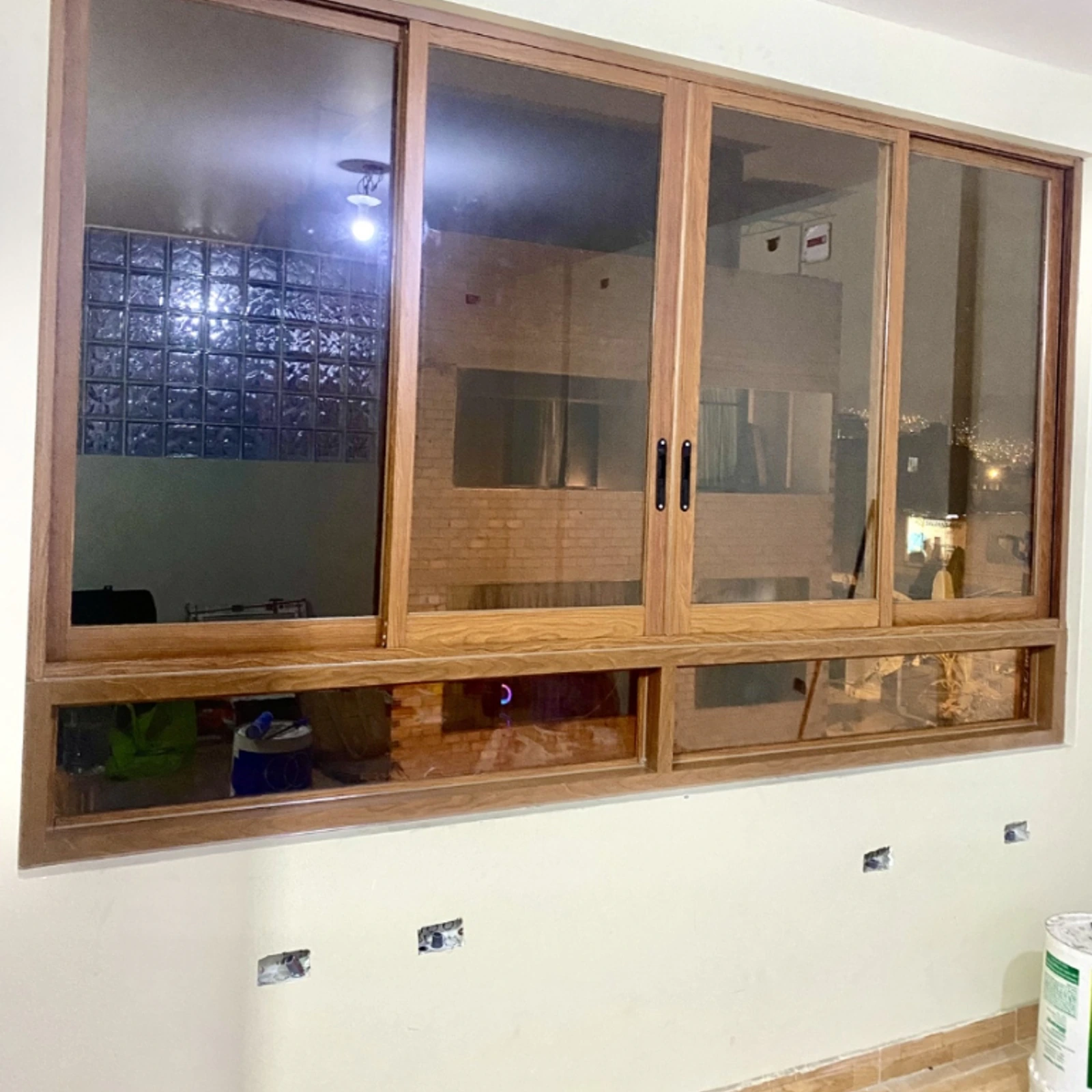 Ventana corrediza de perfilería color madera que separa la cocina del comedor