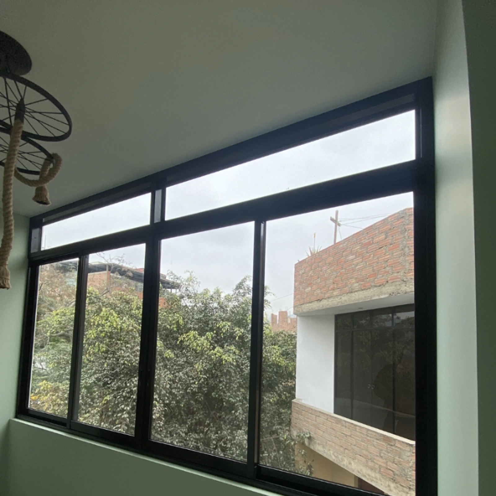 Ventana corrediza de perfilería negra en una habitación de paredes verdes
