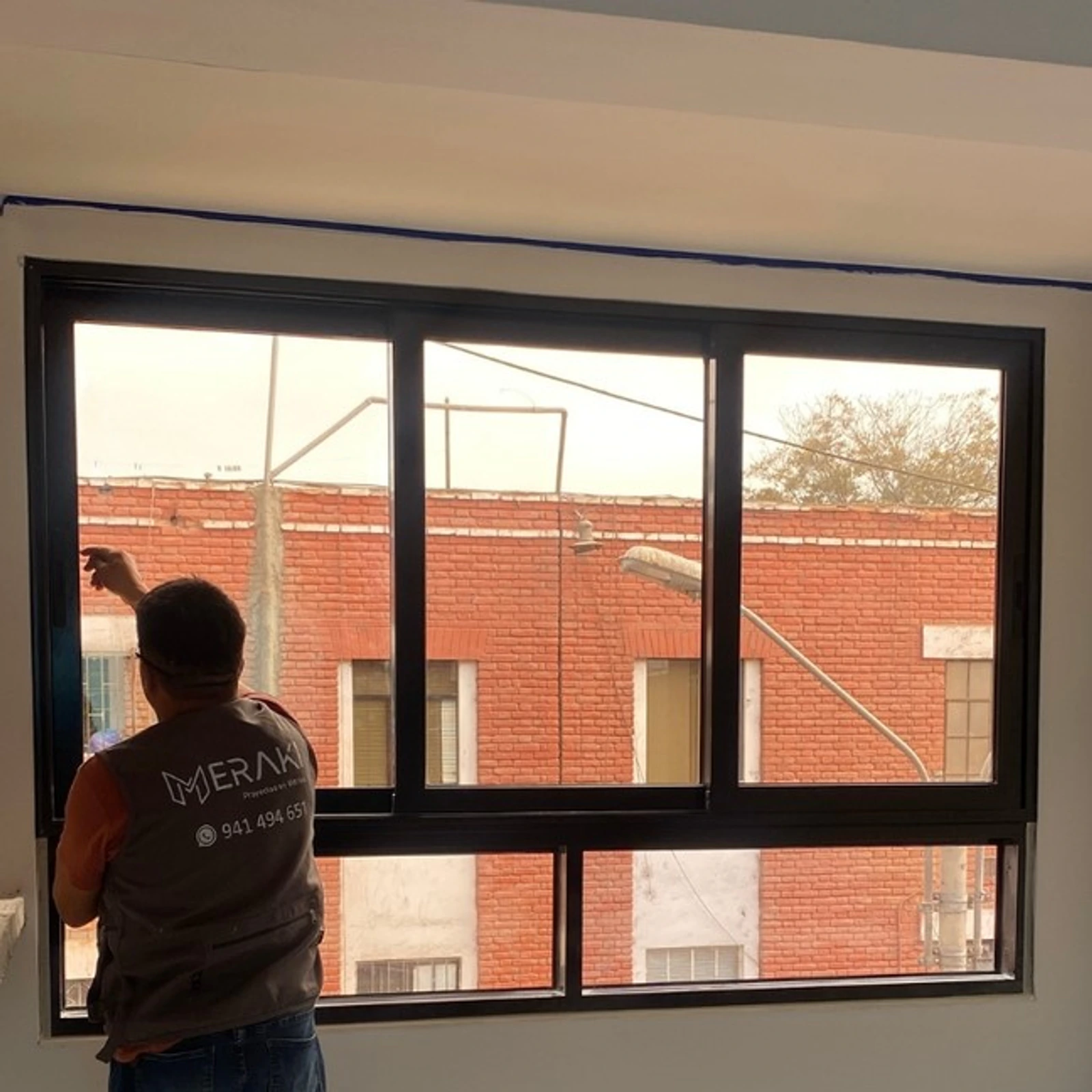 Instalador de Meraki montando una ventana corrediza de perfilería negra en obra