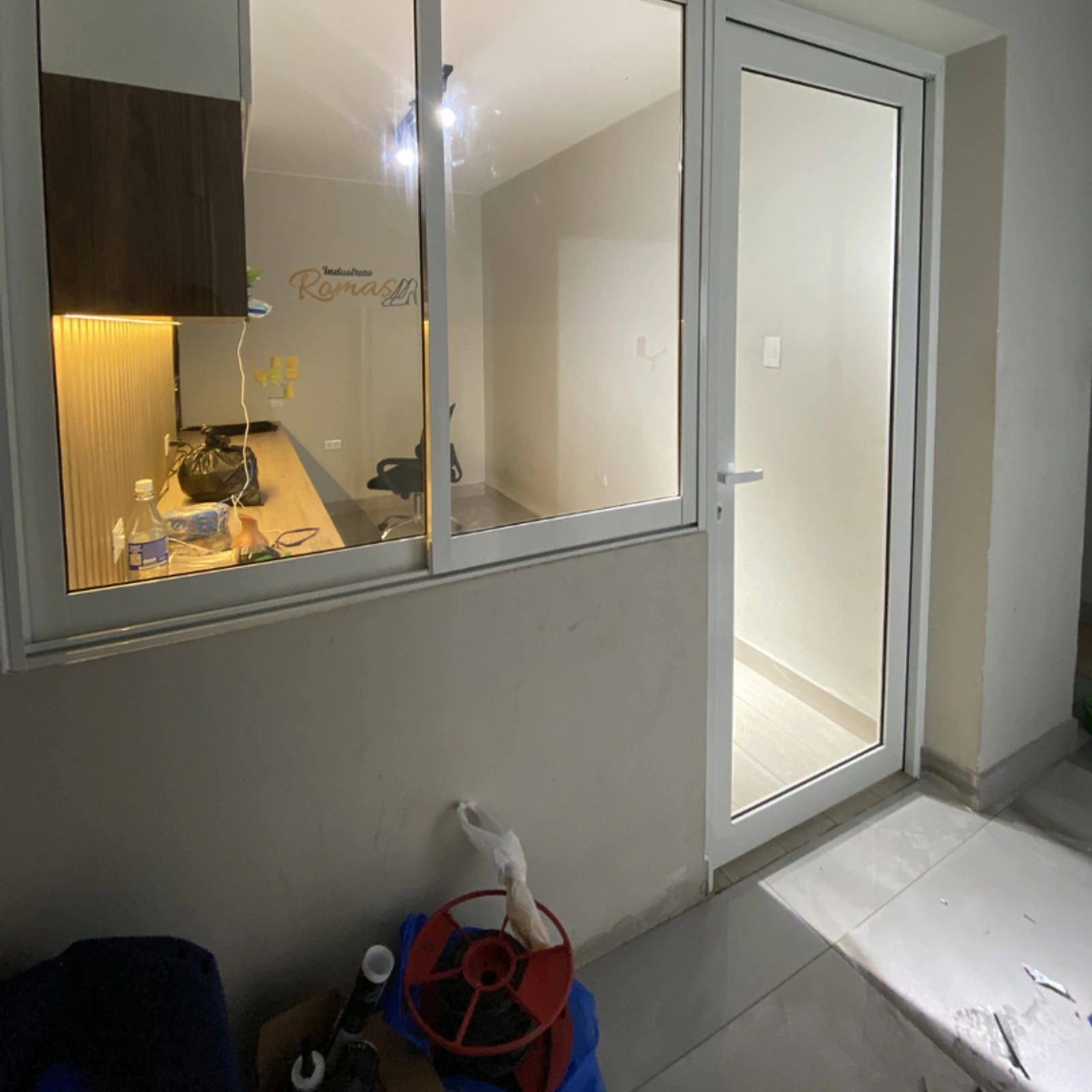 Ventana corrediza de perfilería blanca que comunica con una cocina en obra