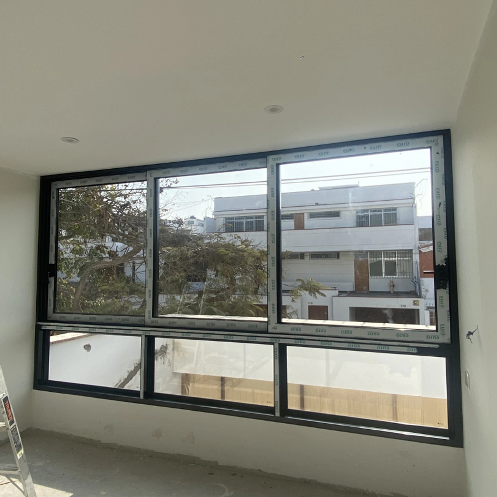 Ventana corrediza panorámica de perfilería negra en una sala recién terminada