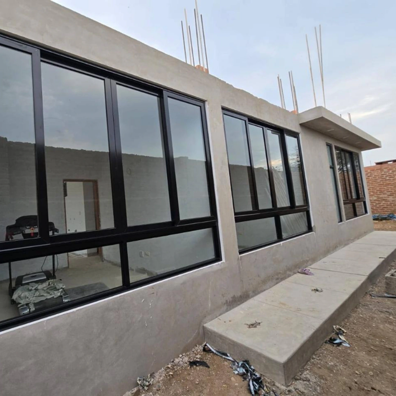 Hilera de ventanas corredizas de perfilería negra en una vivienda en construcción