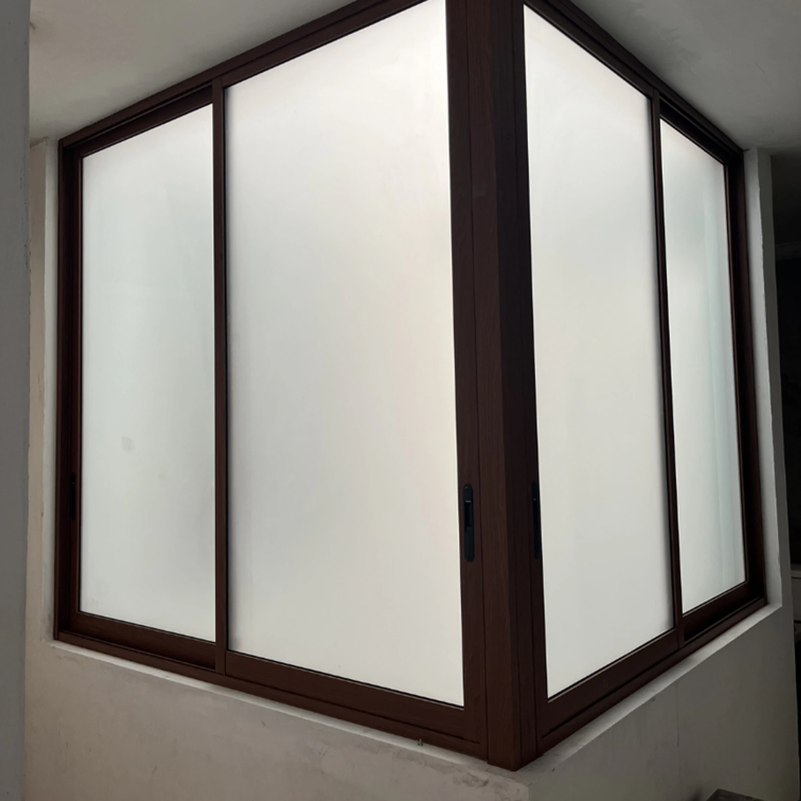 Ventana corrediza en esquina con perfilería color madera y vidrio esmerilado