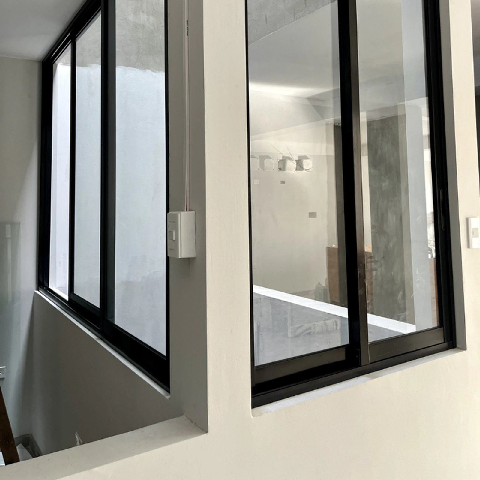 Ventanas corredizas de perfilería negra en esquina, con vidrio esmerilado
