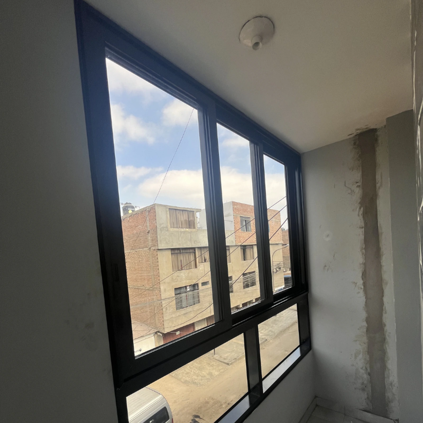 Ventana corrediza corrida de perfilería negra con vista a la calle