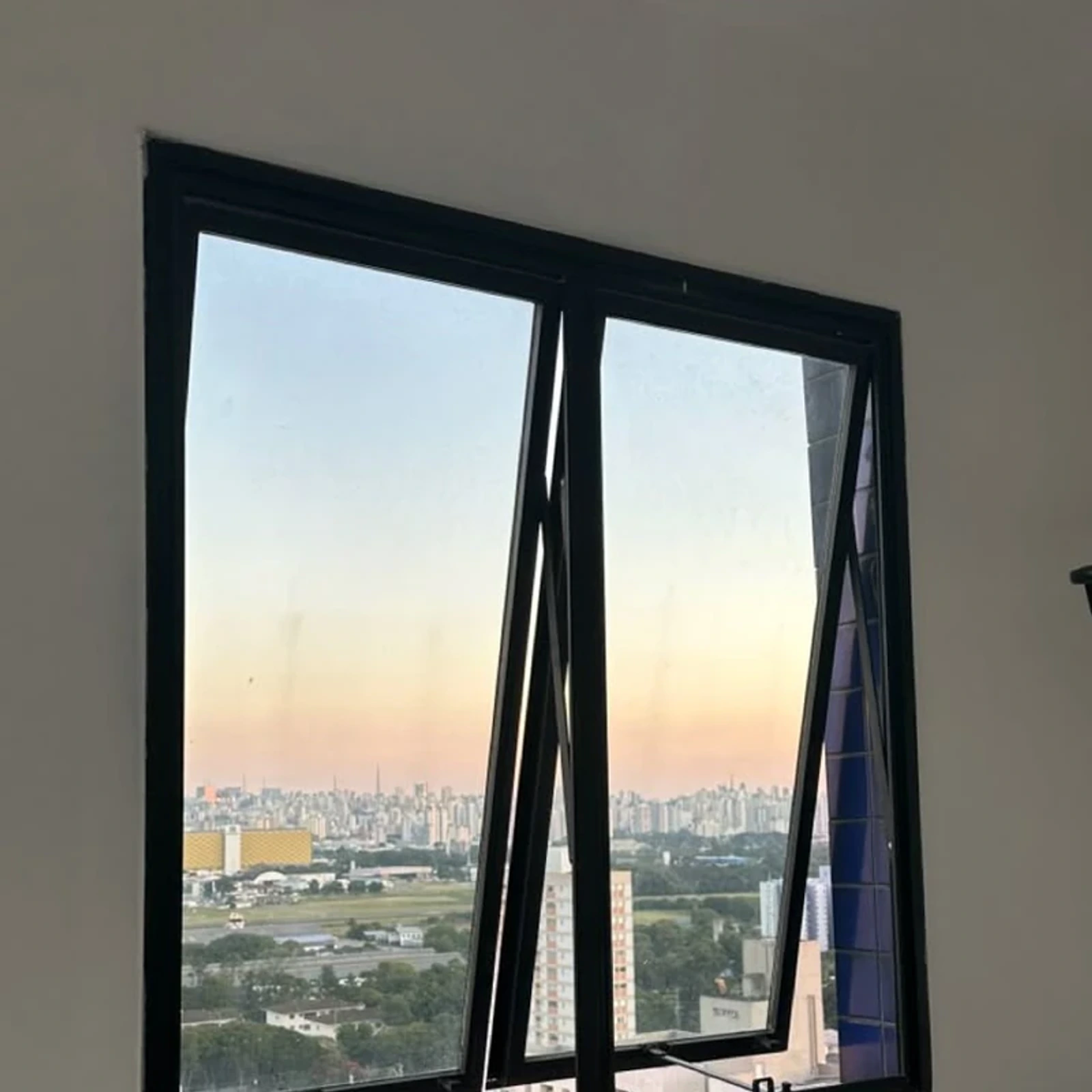Ventana proyectante de dos hojas con perfilería negra, abierta hacia afuera