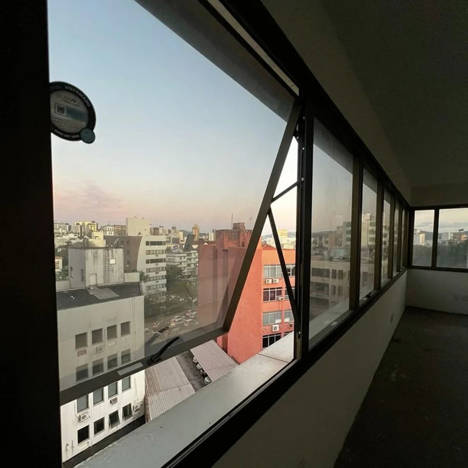 Hilera de ventanas proyectantes de aluminio negro en el pasillo de un edificio