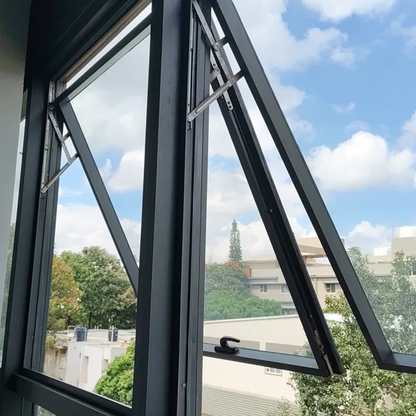 Ventana proyectante de aluminio negro abierta hacia afuera, con vista al cielo
